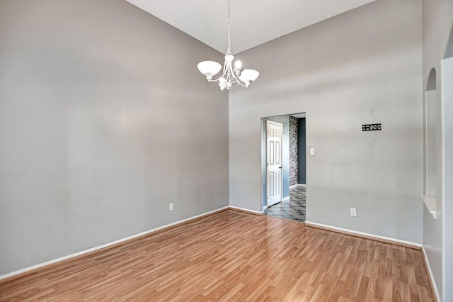 spare room featuring vaulted ceiling, a notable chandelier, and hardwood / wood-style floors