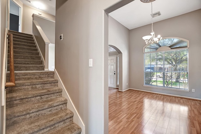 stairs featuring hardwood / wood-style floors, a towering ceiling, and a chandelier