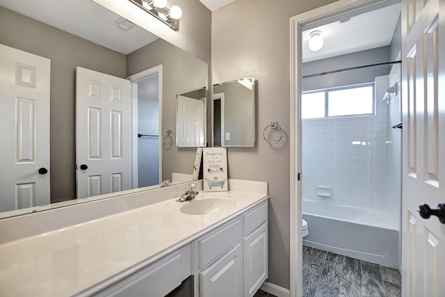 full bathroom featuring toilet, tiled shower / bath, and vanity