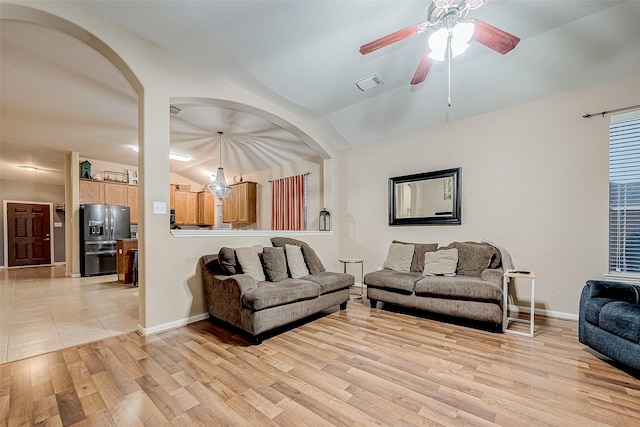 living room with light hardwood / wood-style floors, vaulted ceiling, and ceiling fan with notable chandelier