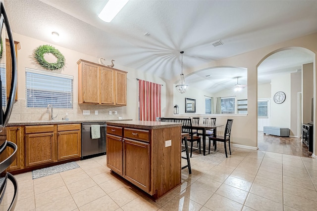 kitchen with a textured ceiling, dishwasher, pendant lighting, a center island, and decorative backsplash