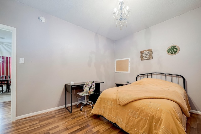 bedroom with hardwood / wood-style flooring and an inviting chandelier