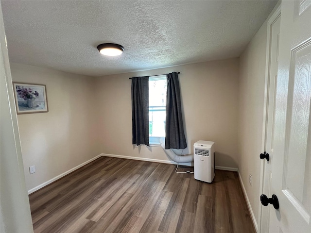 spare room with a textured ceiling and dark hardwood / wood-style floors