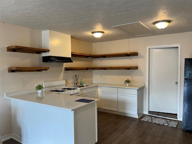 kitchen featuring kitchen peninsula, white range with gas cooktop, black fridge, dark wood-type flooring, and white cabinetry