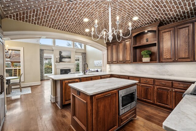 kitchen featuring brick ceiling, sink, a center island, stainless steel microwave, and dark hardwood / wood-style flooring