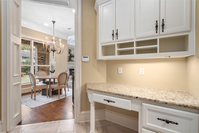 kitchen featuring white cabinetry, ornamental molding, light tile patterned flooring, and light stone counters