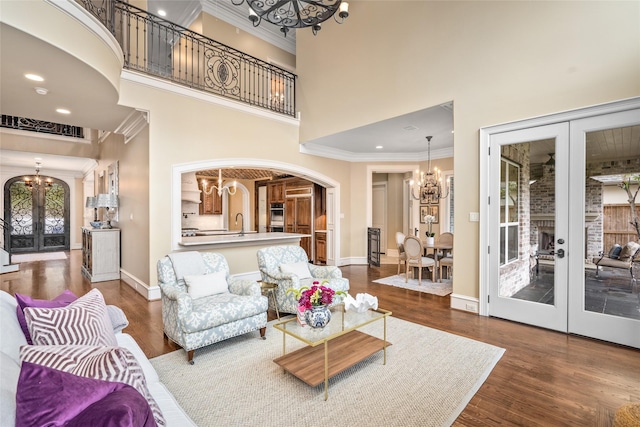 living room with an inviting chandelier, crown molding, dark hardwood / wood-style flooring, and french doors