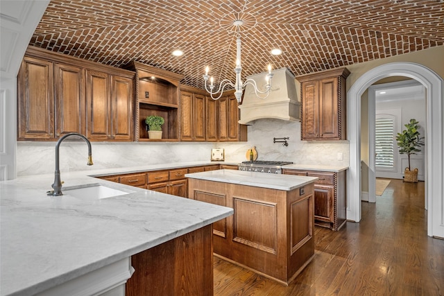 kitchen featuring sink, brick ceiling, a center island, and premium range hood