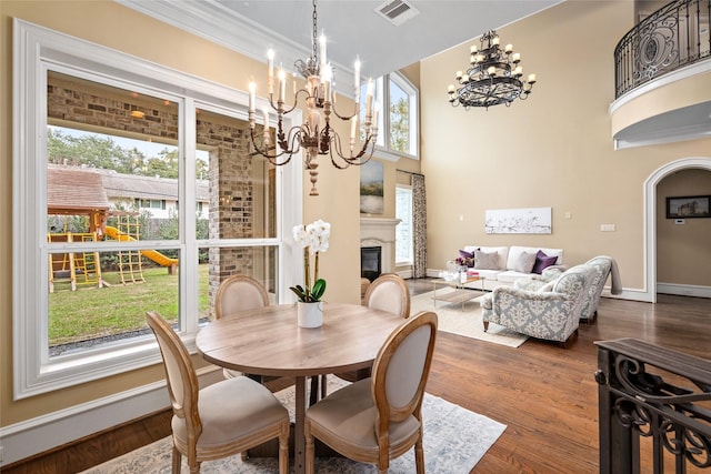 dining room with dark wood-type flooring, a towering ceiling, and a notable chandelier