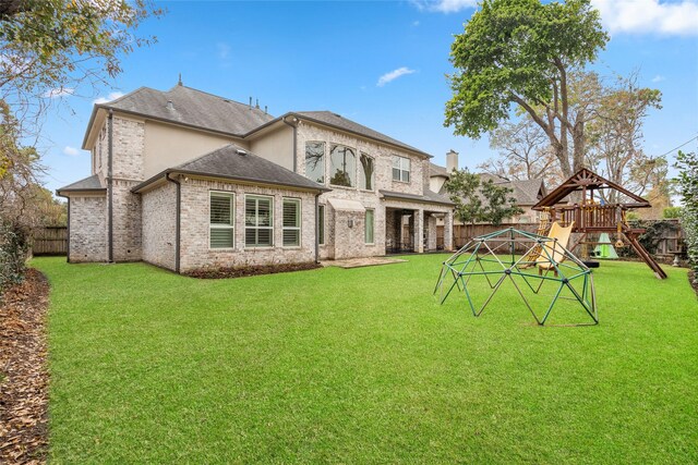 rear view of property featuring a yard and a playground