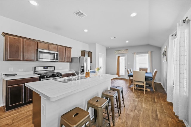 kitchen with an island with sink, light hardwood / wood-style floors, a breakfast bar area, appliances with stainless steel finishes, and sink