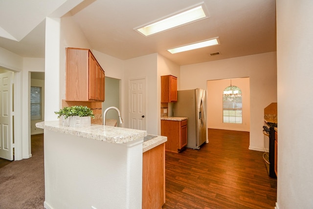 kitchen featuring sink, kitchen peninsula, dark hardwood / wood-style floors, a chandelier, and appliances with stainless steel finishes