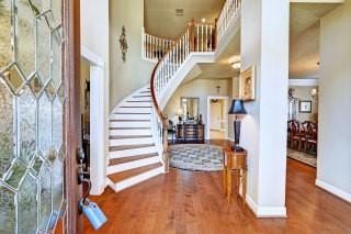 foyer featuring a towering ceiling and wood-type flooring