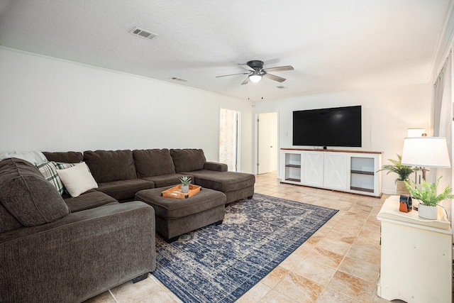 living room featuring ceiling fan and a textured ceiling