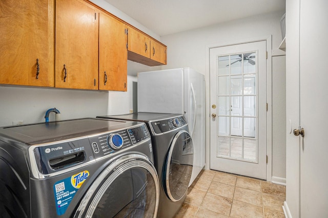 laundry area featuring washer and dryer, cabinets, and light tile patterned flooring