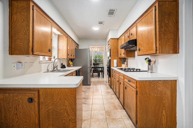 kitchen featuring a textured ceiling, appliances with stainless steel finishes, an inviting chandelier, sink, and kitchen peninsula