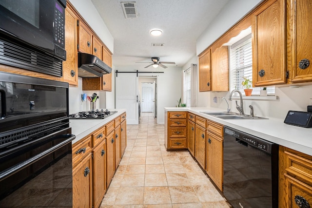 kitchen featuring a textured ceiling, black appliances, sink, ceiling fan, and a barn door