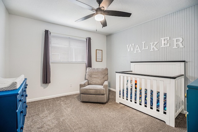 carpeted bedroom with ceiling fan, a crib, and a textured ceiling