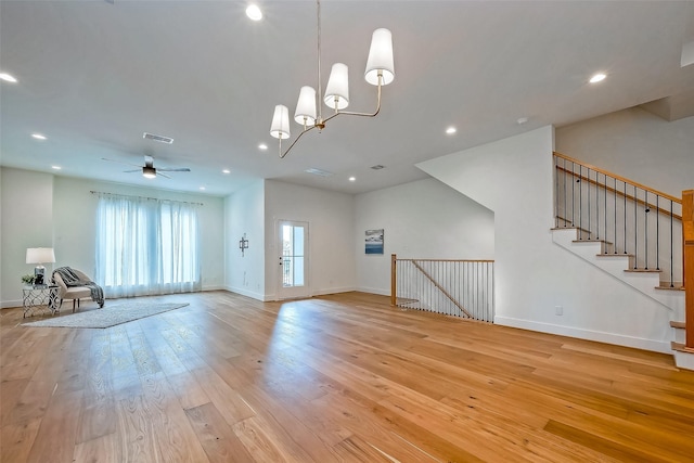 unfurnished living room with light wood-type flooring and ceiling fan with notable chandelier