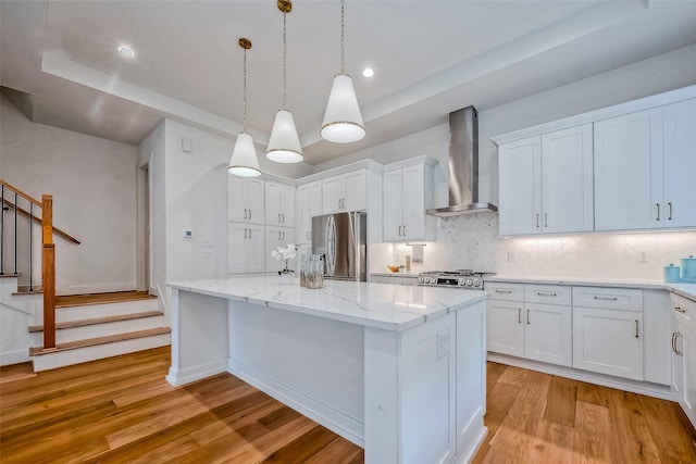 kitchen with white cabinets, a kitchen island, wall chimney exhaust hood, and stainless steel refrigerator with ice dispenser