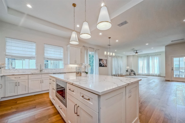 kitchen with stainless steel microwave, a center island, decorative light fixtures, decorative backsplash, and ceiling fan