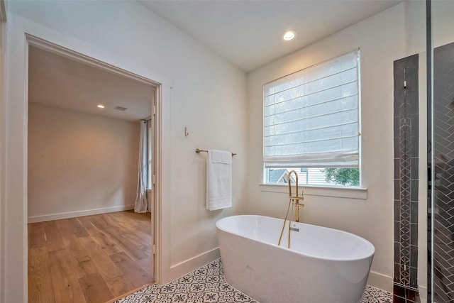 bathroom featuring wood-type flooring and a tub to relax in