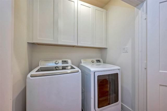 clothes washing area with cabinets and washer and clothes dryer