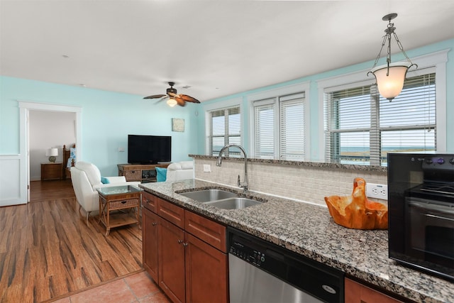 kitchen featuring dishwasher, sink, stone countertops, hanging light fixtures, and plenty of natural light