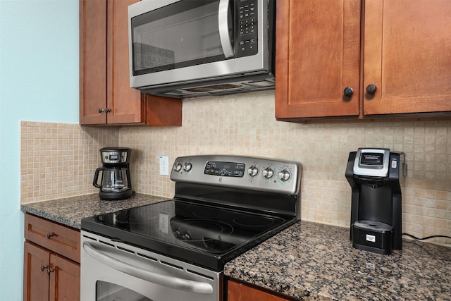 kitchen featuring decorative backsplash, appliances with stainless steel finishes, and dark stone counters