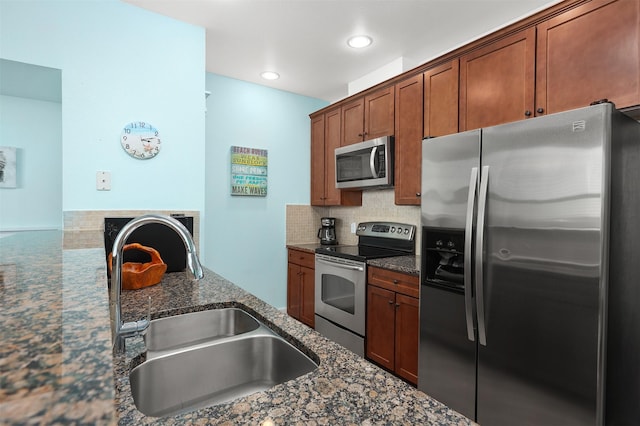 kitchen featuring backsplash, dark stone counters, sink, and stainless steel appliances