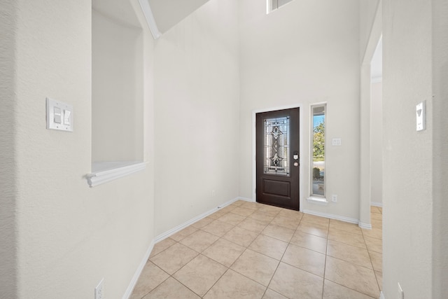 foyer entrance with a towering ceiling and light tile patterned floors