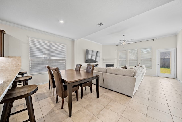 tiled dining area with ceiling fan and ornamental molding