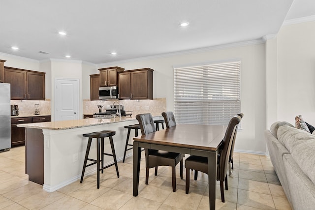 dining space with ornamental molding and light tile patterned floors