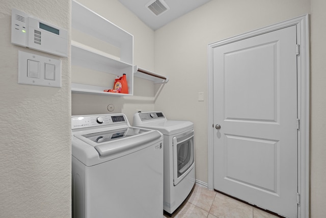 clothes washing area featuring washing machine and dryer and light tile patterned floors