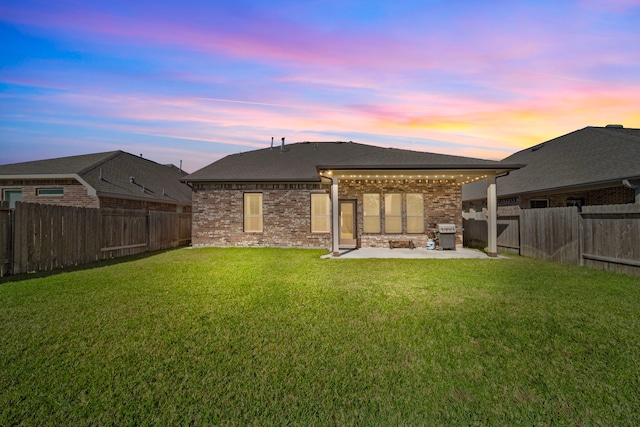 back house at dusk with a yard and a patio