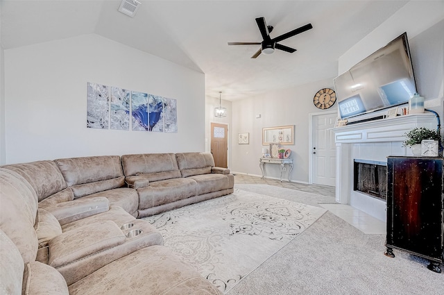 living room featuring vaulted ceiling, a tile fireplace, light colored carpet, and ceiling fan