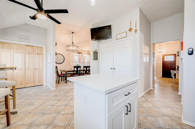 kitchen featuring hanging light fixtures, light tile patterned floors, ceiling fan, white cabinetry, and lofted ceiling