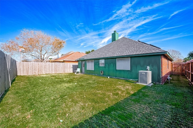 rear view of property featuring central air condition unit and a lawn