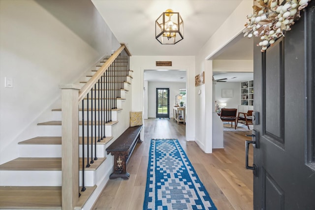 foyer with ceiling fan with notable chandelier and light hardwood / wood-style floors