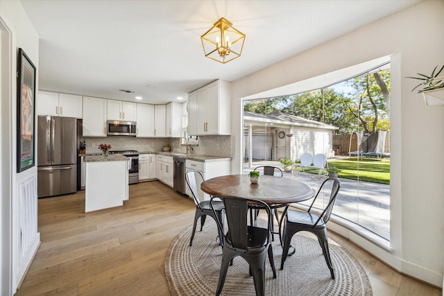 dining area with light wood-type flooring, a notable chandelier, and sink