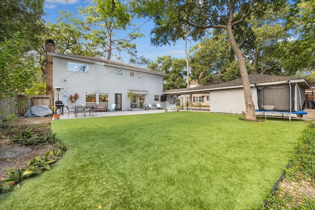 rear view of house featuring a patio area, a lawn, and a trampoline