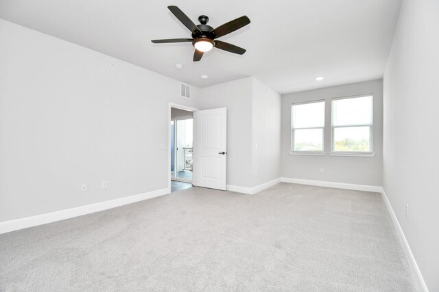 empty room featuring light carpet, a ceiling fan, visible vents, and baseboards