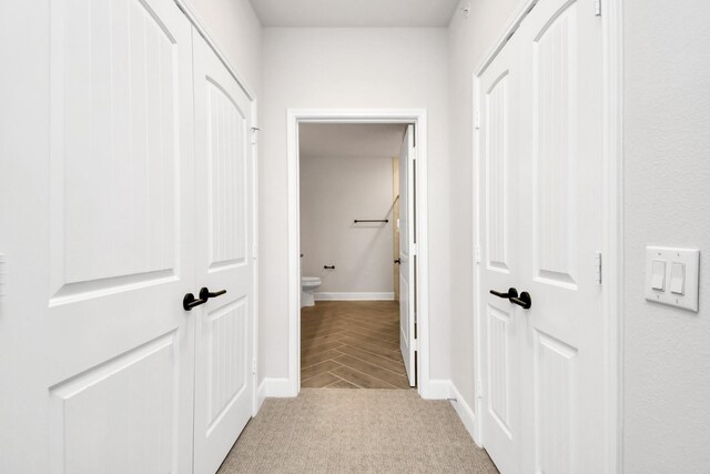 corridor featuring baseboards and light colored carpet