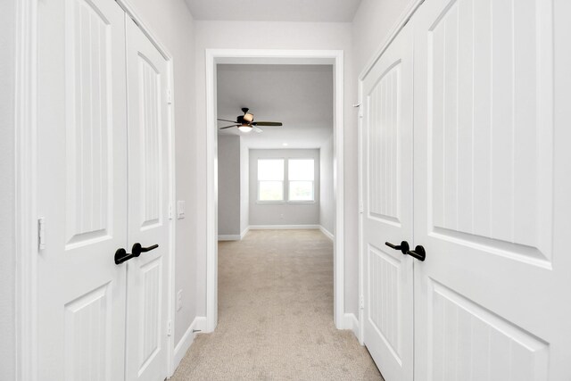 hallway featuring light carpet and baseboards