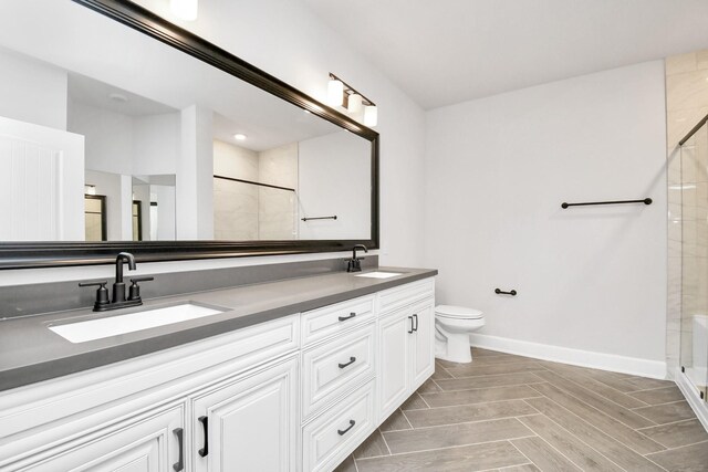 full bath with toilet, baseboards, a sink, and tiled shower