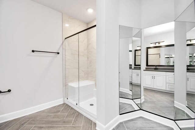 full bath featuring a stall shower, vanity, and baseboards