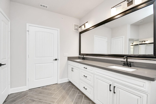 full bath featuring double vanity, a sink, visible vents, and baseboards