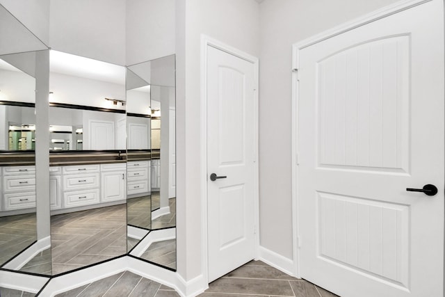 full bath featuring parquet floors, vanity, and baseboards