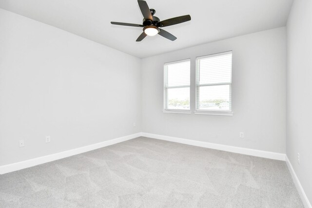 carpeted empty room featuring ceiling fan and baseboards