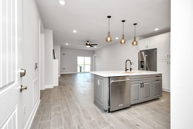 kitchen featuring wood tiled floor, stainless steel appliances, light countertops, a sink, and recessed lighting